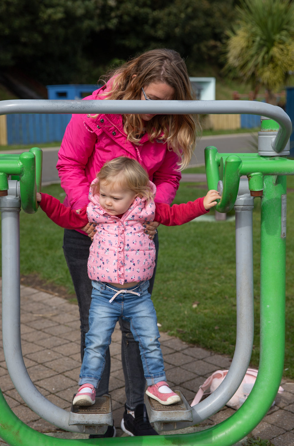 Claire helping Sienna play on a exercise machine at the Park